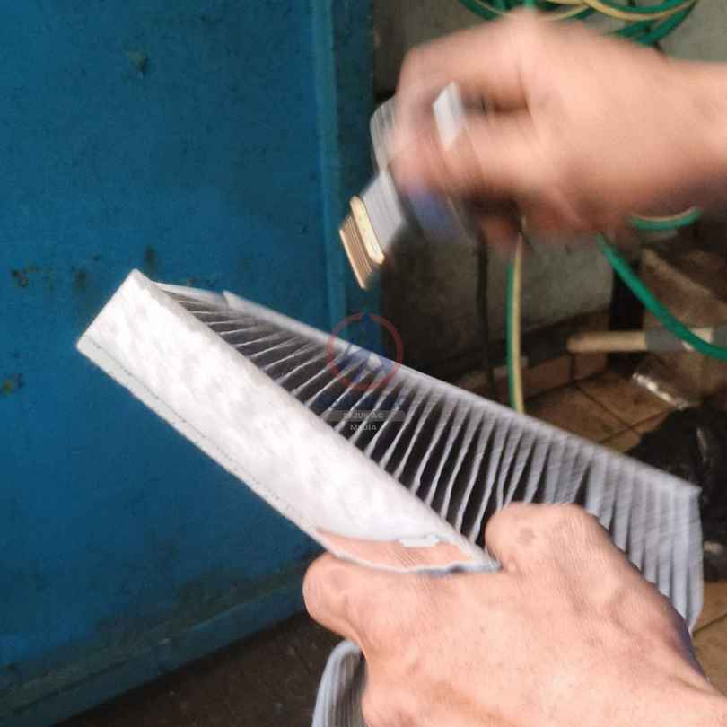 Pembersihan serat filter kabin AC mobil oleh mekanik profesional